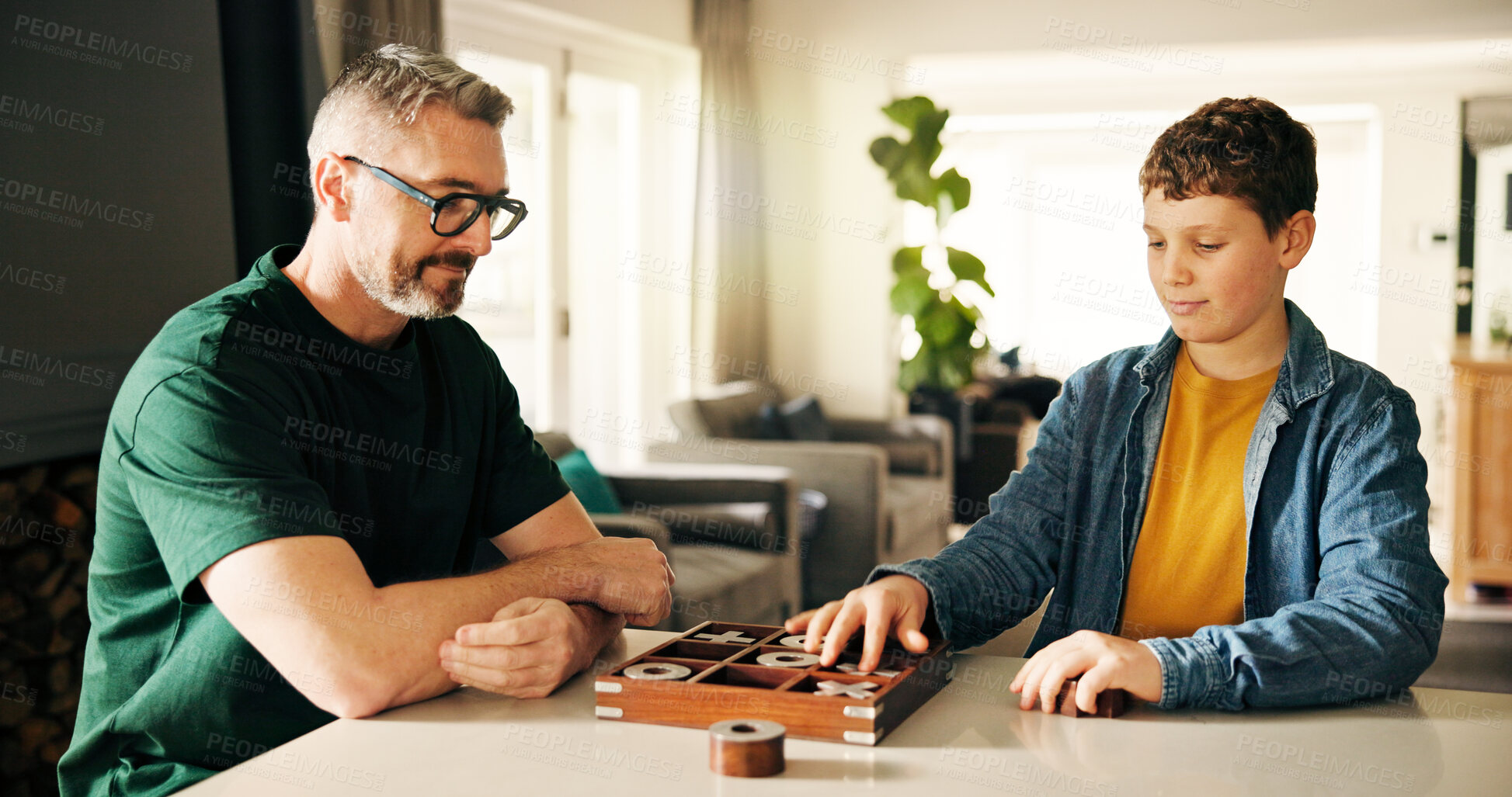 Buy stock photo Board game, development or learning with father and son playing tic tac toe in home together. Fun, strategy or thinking with boy child and parent man in apartment for noughts and crosses contest