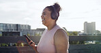 Happy, fitness and woman with headphones in city to listen to music, audio and workout playlist. Town, runner and person on smartphone for health app, track exercise and radio for training outdoor