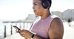 Phone, headphones and woman on promenade with music, podcast or playlist for running exercise. Sports, audio and female athlete with cellphone for radio, cardio and workout break outdoor by beach