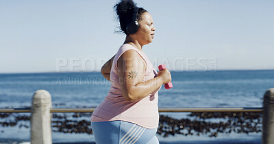 Buy stock photo Running, headphones and woman by beach with music, podcast or fitness for exercise. Sports, audio and plus size athlete to lose weight with radio, cardio and workout or training outdoor by promenade