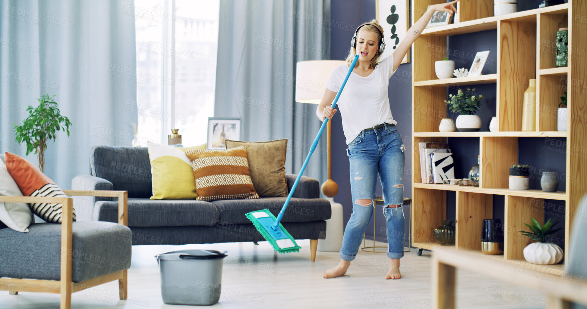 Buy stock photo Woman, cleaning and singing with headphones in home, broom and happy with streaming in living room. Girl, excited and listen to music with audio subscription, karaoke or dance for chores at house