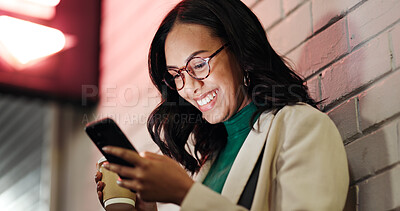 Buy stock photo Happy woman, phone and coffee in city, night and drink for chat, funny story or meme on web by wall. Business person, smartphone and cup with laugh for gossip, mobile app or social media in Venezuela