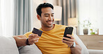 Happy, credit card and man in home with phone for online shopping, digital purchase and payment. Sofa, house and person with debit info on smartphone for ecommerce, website sale and internet banking