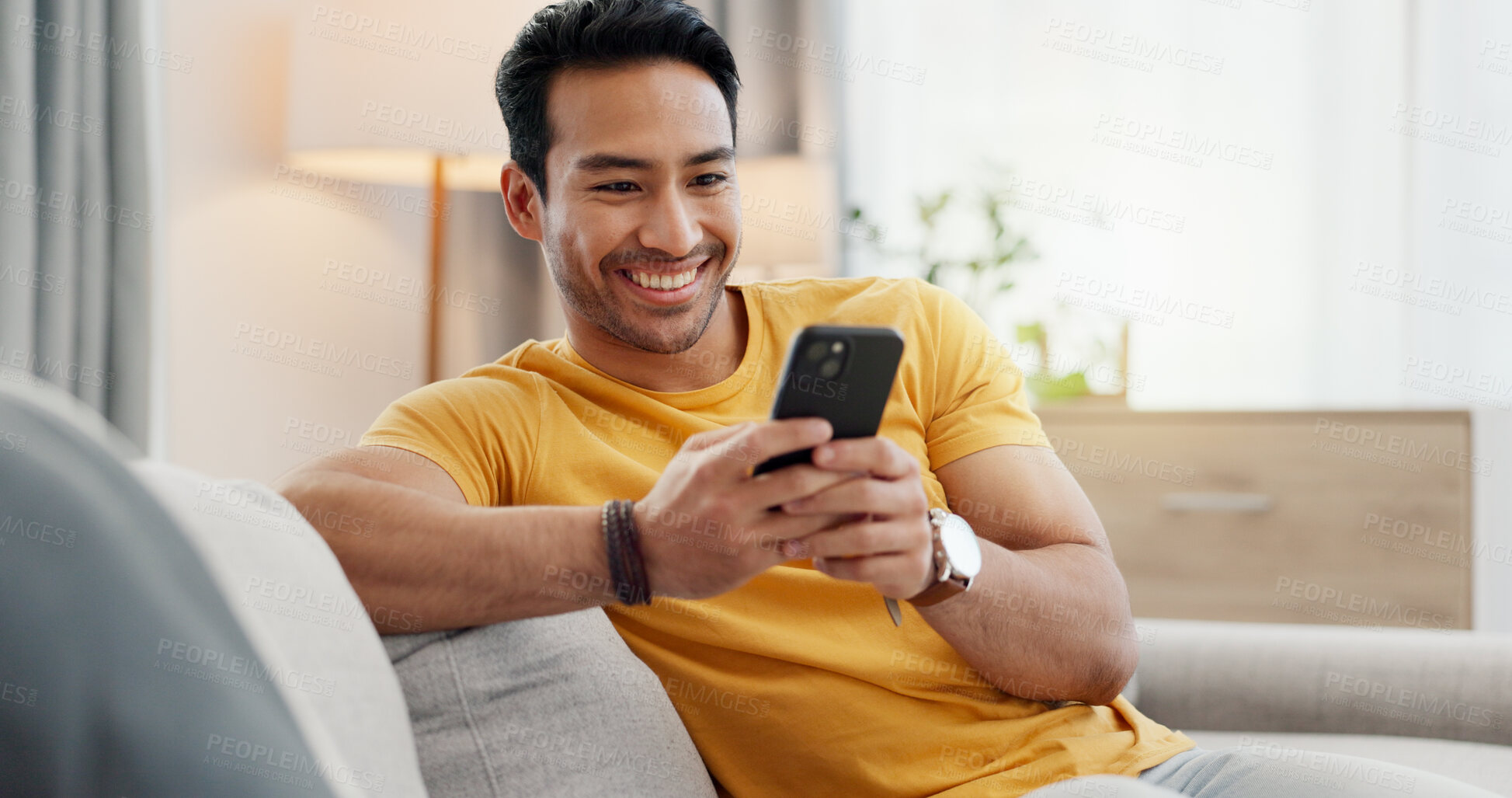 Buy stock photo Phone, relax and happy man in home for internet, social media post and reading news. Cellphone, living room and person with app for online text, communication and check message with notification