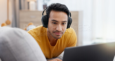 Buy stock photo Headphones, laptop and relax with man on sofa in living room of home for online subscription. Computer, streaming and watching video with person in apartment for break, entertainment or media