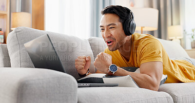 Buy stock photo Man, laptop and headphones on sofa for sport, social media and video streaming or website in home. Excited, cheer and male person on couch with technology, break and watching tournament on app
