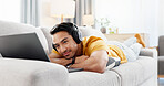 Man, laptop and headphones on sofa for break, social media and video streaming or website in home. Movie, internet audio and male person on couch with technology, relax and watching film on app