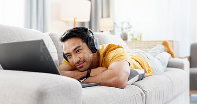 Buy stock photo Man, laptop and headphones on sofa for break, social media and video streaming or website in home. Movie, internet audio and male person on couch with technology, relax and watching film on app