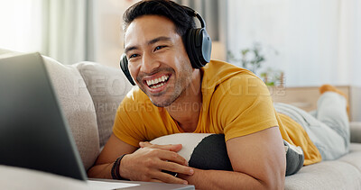 Buy stock photo Relax, laptop and laughing with man on sofa for streaming service, headphones and film. Movie subscription, media website and home cinema app with person in living room of apartment for comedy video
