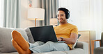Search, headphones and laptop with man on sofa for streaming service, film website and comfortable. Movie subscription, watching series and entertainment with person in living room of home for smile
