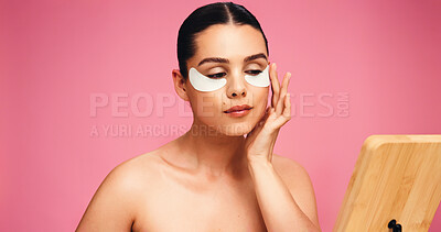 Buy stock photo Woman, check and eye mask for skincare in studio for dark circle, reduce puffiness and hydration. Person, mirror and patches with mockup space of beauty, collagen benefits and glow on pink background