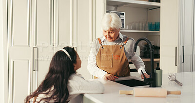 Buy stock photo Grandmother, girl and cooking with talk in kitchen, teaching and advice with help at family house. Child, grandma and love for baking, conversation or guide with learning, development or food in home