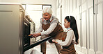 Baking, kitchen and grandmother with girl by oven to check cookies, biscuits and cake on weekend. Family, happy and senior woman with child in home for bonding, helping and learning recipe together