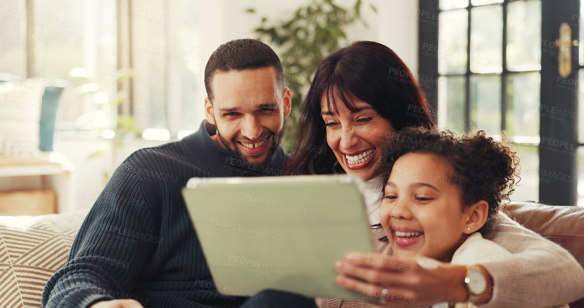 Buy stock photo Parents, girl and happy with tablet on sofa, laugh or love with funny film, bonding and streaming in lounge. Father, mother and daughter with joke, app and movies on couch at interracial family house