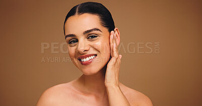 Buy stock photo Portrait, makeup and touch face of female model on brown background for cosmetics and coverage. Skin glow, foundation and confidence of woman in studio with mockup, space and smile for facial