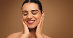 Happy, makeup and touch face of woman on brown background for cosmetics and coverage. Skin glow, foundation and confidence of model in studio with mockup, space and self care for facial results