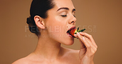 Buy stock photo Skincare, eating and woman in studio with strawberry, vitamin C or antioxidant for skin. Dermatology, detox or nutritionist on brown backdrop with fruit, collagen boost or protection in UV damage.