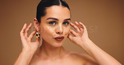 Buy stock photo Earrings, beauty and portrait of woman with makeup for glamour, glow and shine on brown background. Ear jewelry, studio and female model with lipstick cosmetics, face transformation and confidence