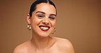 Makeup, earrings and happy woman in studio for beauty, skin glow and brown background space. Aesthetic, ear jewelry and model with lipstick cosmetics, face transformation and portrait with change