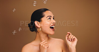 Buy stock photo Bubbles, happy and woman in studio for beauty, skincare and cosmetics for wellness, health and glow. Wow, space and person with soap for spa aesthetic, self care and dermatology on brown background
