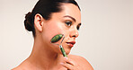 Girl, jade roller and skincare with beauty in studio, mockup space and thinking on background. Woman, dermatology and stone tools for blood circulation, reflection and massage for facial benefits