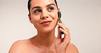 Happy woman, skincare or beauty with jade roller in studio for facial massage on a white background. Female person, model or treatment with tool for lymphatic drainage, health or wellness on space