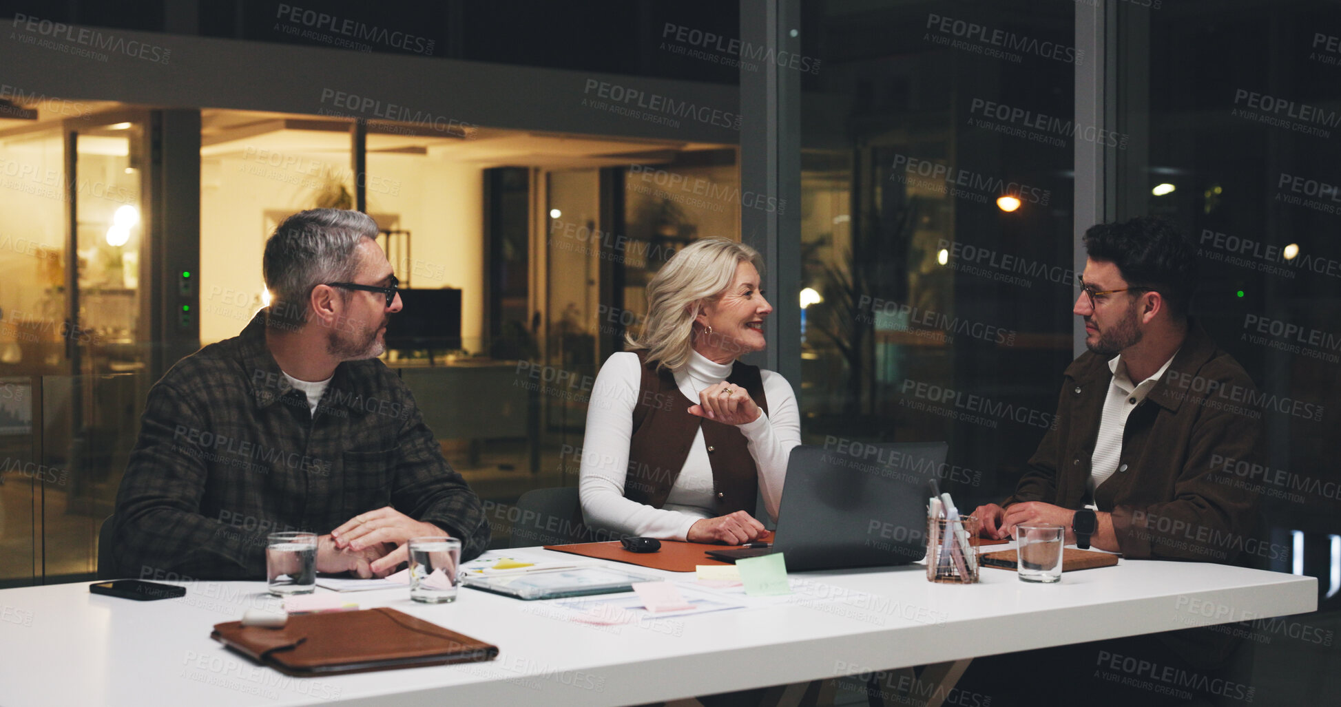 Buy stock photo Business, team and laptop in meeting at night for manuscript revision, editorial planning or ideas. Publishing agency, people and editor with discussion for article deadline or breaking news coverage