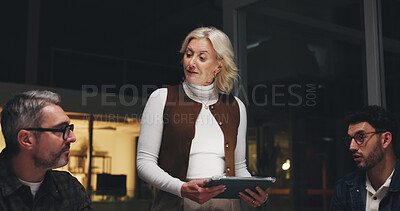 Buy stock photo Woman, tablet and discussion with team at night, creative pitch plan and online research for digital marketing. Brand campaign, social media and mature person with tech for collaboration and deadline