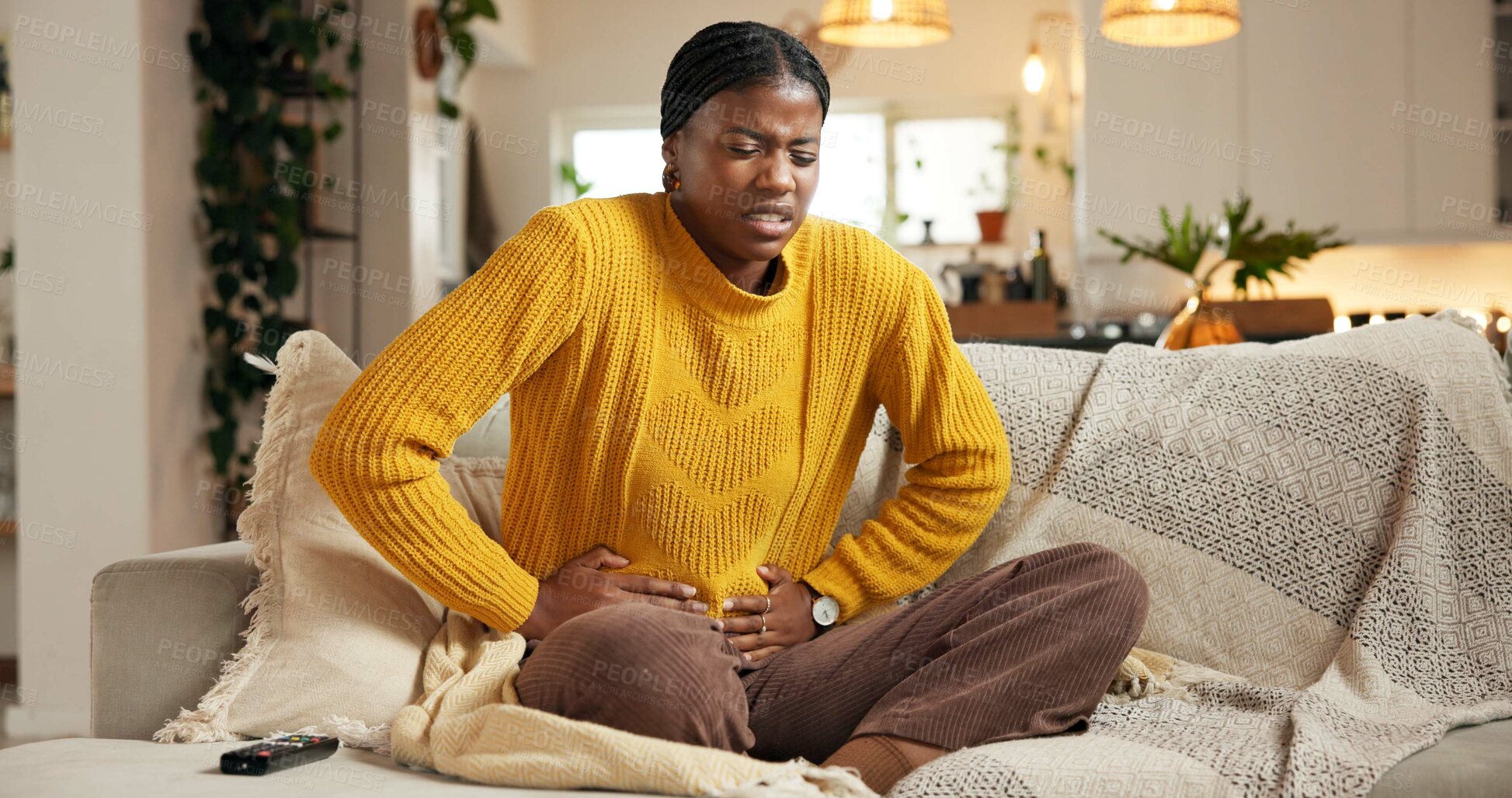 Buy stock photo Stomach ache, couch or black woman with pain in living room, constipation or menstruation cycle for sore belly. Upset, period cramps or person with abdominal problem, digestion trouble or pms in home