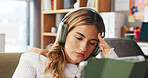 Tired woman, headphones and listening with tablet in home for audio book, streaming or reading. Female person, user or technology with sound for online subscription, news or ebook on sofa in house