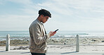 Man, reading and phone on promenade for travel, social media and message contact on holiday. Male person, mobile browsing and texting, online chatting and fresh air for ocean vacation of getaway trip