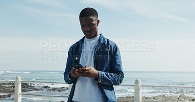 Buy stock photo Scroll, message and man at promenade with phone, communication or typing on mobile app. Concentration, digital and African male at beach with tech, connection and text update on social media.