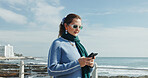 Woman, reading and phone on promenade for travel, social media and message contact on holiday. Female person, mobile app and texting, online chatting and fresh air for ocean vacation of getaway trip