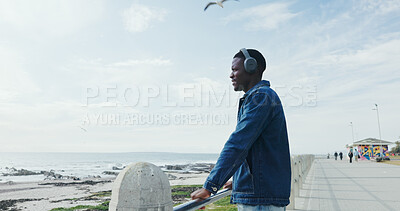 Buy stock photo Travel, man and explore beach with headphones for holiday destination, sightseeing and thinking. Sky space, black person or listening to music on promenade for weekend trip, ocean view and reflection