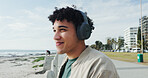 Thinking, man and happy with headphones at beach for holiday destination, sightseeing ocean or relax. Travel, tourist or listening to music on promenade for weekend trip, radio playlist or reflection