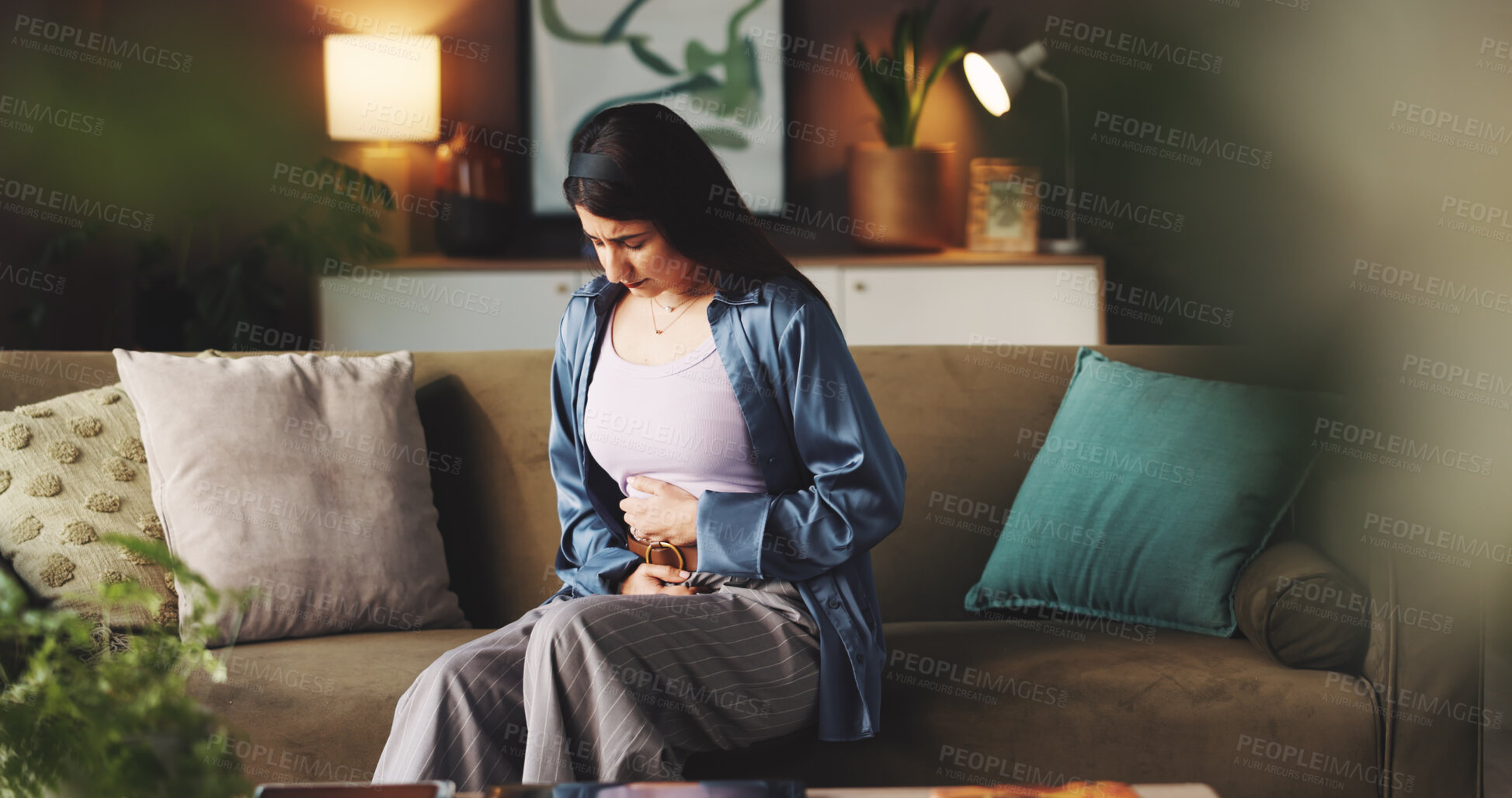 Buy stock photo Cramps, sick and woman with stomach pain on sofa from menstrual cycle, bloating or endometriosis. Period, discomfort and person with tummy ache in home with gastrointestinal issue and inflammation