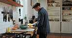Cooking, food and man with vegetables in kitchen for meal prep, healthy lunch and dinner recipe. Counter, home and person with ingredients, cuisine and cutting for nutrition, vitamins and wellness 