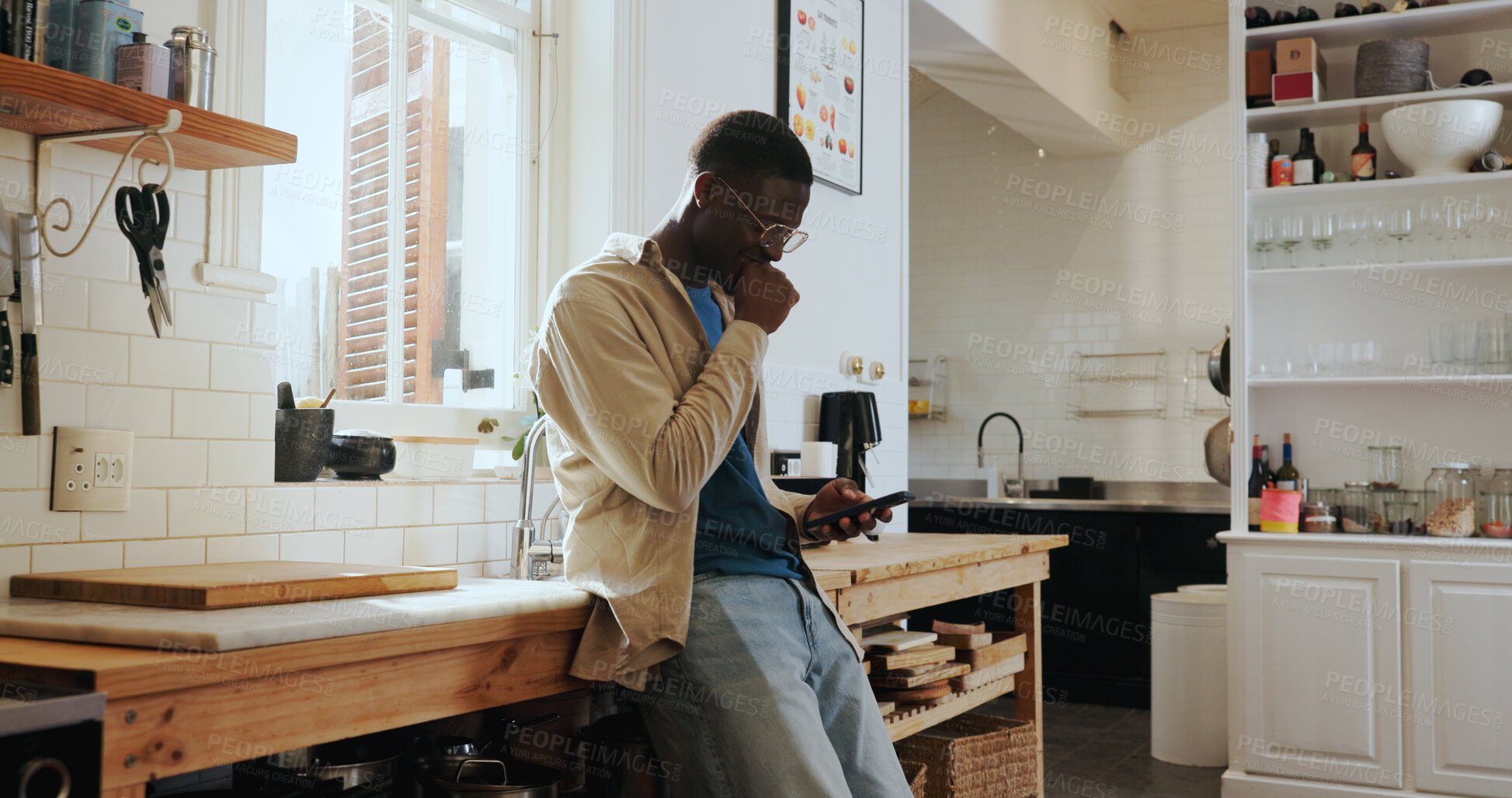 Buy stock photo Scroll, reading and black man in kitchen with phone, funny social media post and laughing at text message. Happy,  conversation and African person on mobile with internet comedy, meme or good news