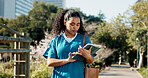Woman, nurse and student with tablet in park for medical internship, study or telehealth. Female person, junior or reading with technology in nursing school for learning or health volunteer in city