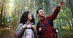 Couple, hiking and point in forest for direction with search, break and happy with backpack for tourism. Man, woman and interracial relationship with love, smile or landmark on trekking adventure