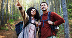 Couple, hiking and point in woods for direction with search, break and happy with backpack for tourism. Man, woman and interracial relationship with love, smile or trekking adventure in forest