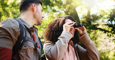 Buy stock photo Couple, hiking and happy with binoculars in forest for sightseeing, adventure and outdoor in summer. Woman, man and interracial love for birdwatching, direction or smile with trekking in woods