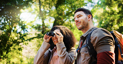Buy stock photo Happy couple, hiking and binoculars in forest for sightseeing, adventure and outdoor for summer. Woman, man and interracial love for birdwatching, tourist or smile for view with trekking in woods