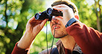 Explore, hike and man in forest with binocular, bird watching or sightseeing in holiday hobby. Observation, nature and tourist in woods with field glasses, outdoor or animal search on solo trip.