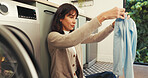 Packing, laundry and clothes with woman and washing machine for cleaning, hygiene and tidy. Housekeeping, folding and sanitary chores with person in washroom of home for basket, dryer and fabric