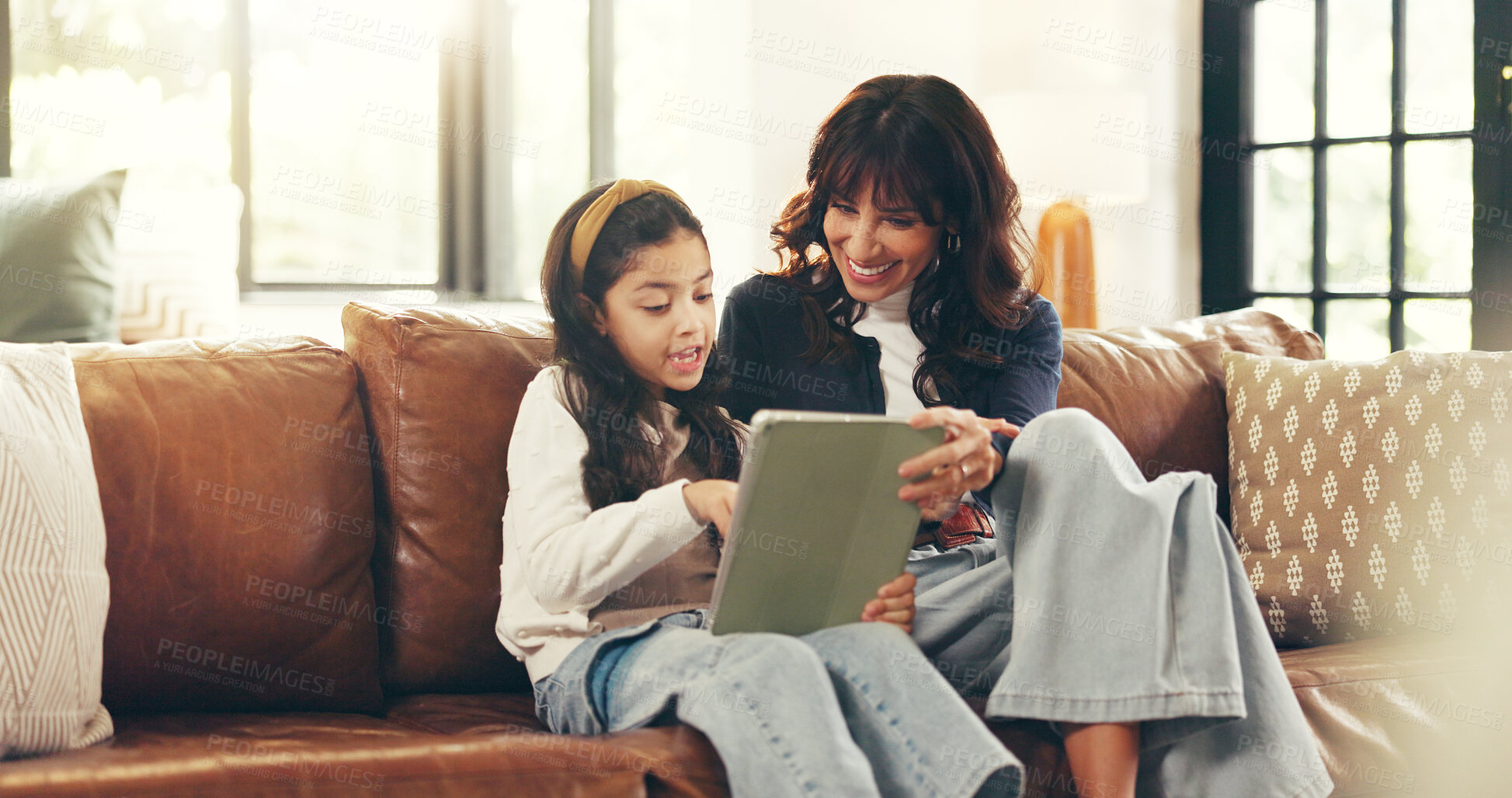 Buy stock photo Home, tablet and mother on couch, girl and bonding together with smile, internet and help. Elearning, happy parent and family on sofa, mama and daughter with tech, talking and digital app for puzzle