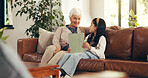 Home, tablet and grandmother on sofa, girl and bonding together with education games on internet. Learning, old woman or family on couch, granny and child with tech, talking or digital app for puzzle