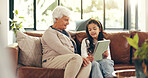 Home, tablet and grandmother with girl, talking and bonding together with education games, help and tech. Learning, granny or family on sofa, child or conversation with digital app for ebook or relax