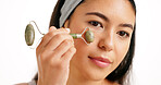Woman, face and massage with jade roller for anti aging skincare on a white studio background. Female person, model or hand with beauty tool for facial treatment, lymphatic drainage or circulation