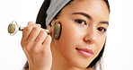 Woman, face and skincare with jade roller for massage or anti aging on a white studio background. Female person, model or hand with beauty tool for facial treatment, lymphatic drainage or circulation